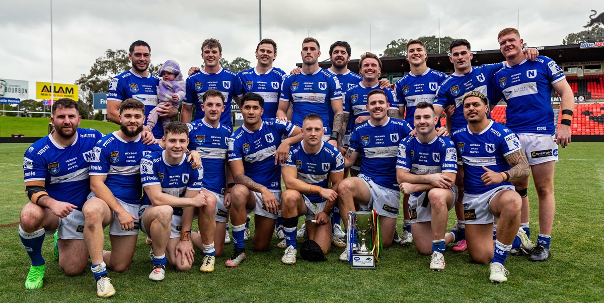 The Newtown Jets players (along with Mawene Hiroti's baby daughter) display the Ken Wilson-Ray Blacklock Cup which they won on Saturday after beating the Penrith Panthers for the second time this year.  Photo: Mario Facchini, mafphotography